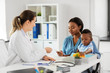 © Syda Productions - medicine, healthcare and pediatry concept - caucasian doctor giving prescription to african american mother with baby son at clinic