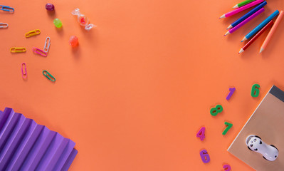 Colored different school supplies on orange background. Back to school background. Flat lay, top view, copy space