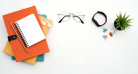 Flat lay black to school and education concept on white table desk with blank notepad and stack of book , green plant and supplies, Top view with copy space, work space