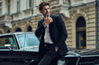 Young handsome man with black classic car wearing black suit