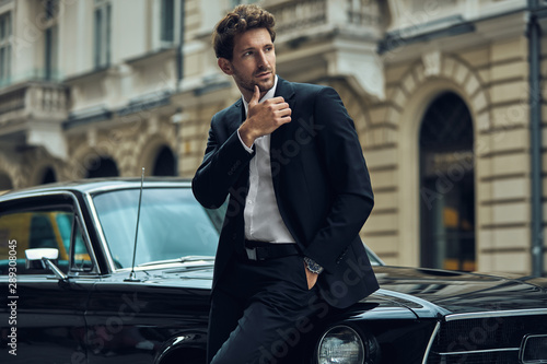 Fotomural Young handsome man with black classic car wearing black suit