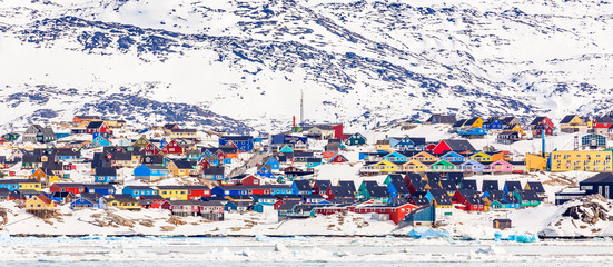 Wall Mural - Arctic city center panorama with colorful Inuit houses on the rocky hills covered in snow with snow and mountain in the background, Ilulissat, Avannaata municipality, Greenland