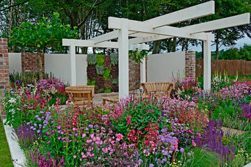 Wall Mural - A contemporary garden with terraced area and stylish wooden furniture surrounded by colourful flowering borders