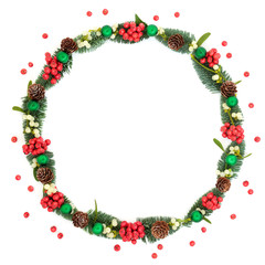 Christmas decorative wreath with holly berries, mistletoe, spruce fir, pine cones, green ball baubles and loose berries on white background with copy space. Traditional symbol for the festive season.