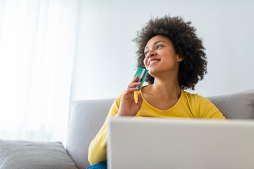 Wall Mural - Female consumer spending buying on internet, lifestyle. Happy woman shopping online with laptop at home. Woman using laptop computer shopping on line, using credit card playing online, smiling indoors