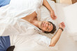 © rilueda - Handsome young man smiling and relaxing on hotel bed
