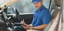 Young Delivery Man Preparing The Products To Customer While Sitting On The Car