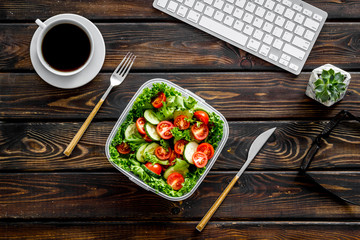 Wall Mural - Food container with healthy food on office desk with keyboard and tea on wooden background top view