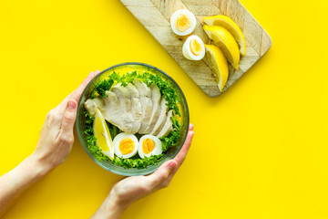 Wall Mural - Healthy dinner in bowl in hands on yellow background top view