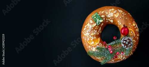 Fotomural Christmas round fruit cake decorated with fir tree branch, glazed fruits and nuts over black background