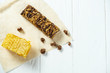 Close up on Granola Bar with honeycombs on craft paper on white wooden background. Healthy sweet dessert snack. Energy bar of muesli. Granola for breakfast. Copy space