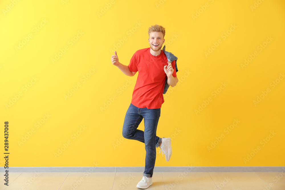 Handsome young man dancing against color wall