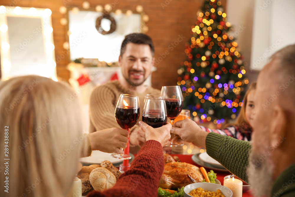 Happy family clinking glasses during Christmas dinner at home