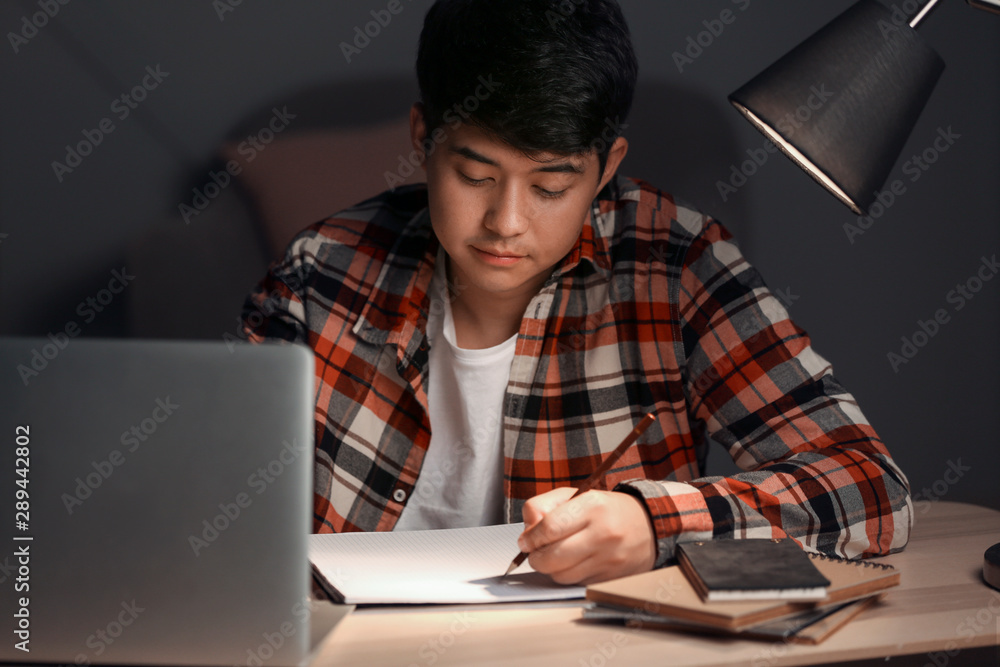 Asian student preparing for exam late in evening