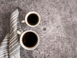 Zwei weiße Tassen mit Kaffee und Stoffserviette auf einem grauen Hintergrund, Kaffeepause, Flat lay