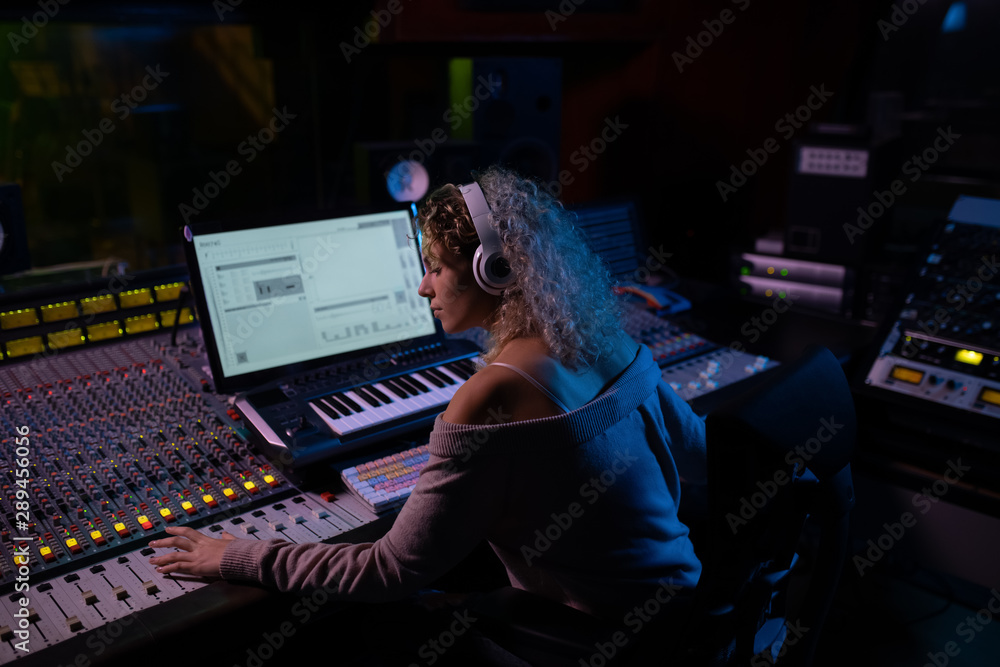 Female music producer working at the mixing desk in a sound studio ...
