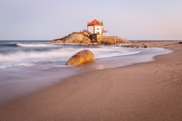 Sunrise at the beach with a church in the sea (Senhor da Pedra Chapel)