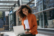 © Oleksii - Portrait of beautiful African American businesswoman using laptop computer and internet, typing on keyboard. Successful business and career. Smiling woman copywriter working freelance project outdoors