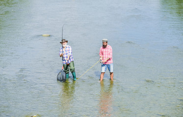 Male friendship. Father and son fishing. Fishing together. Teach man to fish and you feed him for lifetime. Summer weekend. Happy fisherman with fishing rod and net. Hobby and sport activity