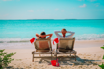 Wall Mural - Christmas on beach -chair lounges and happy couple relax at sea