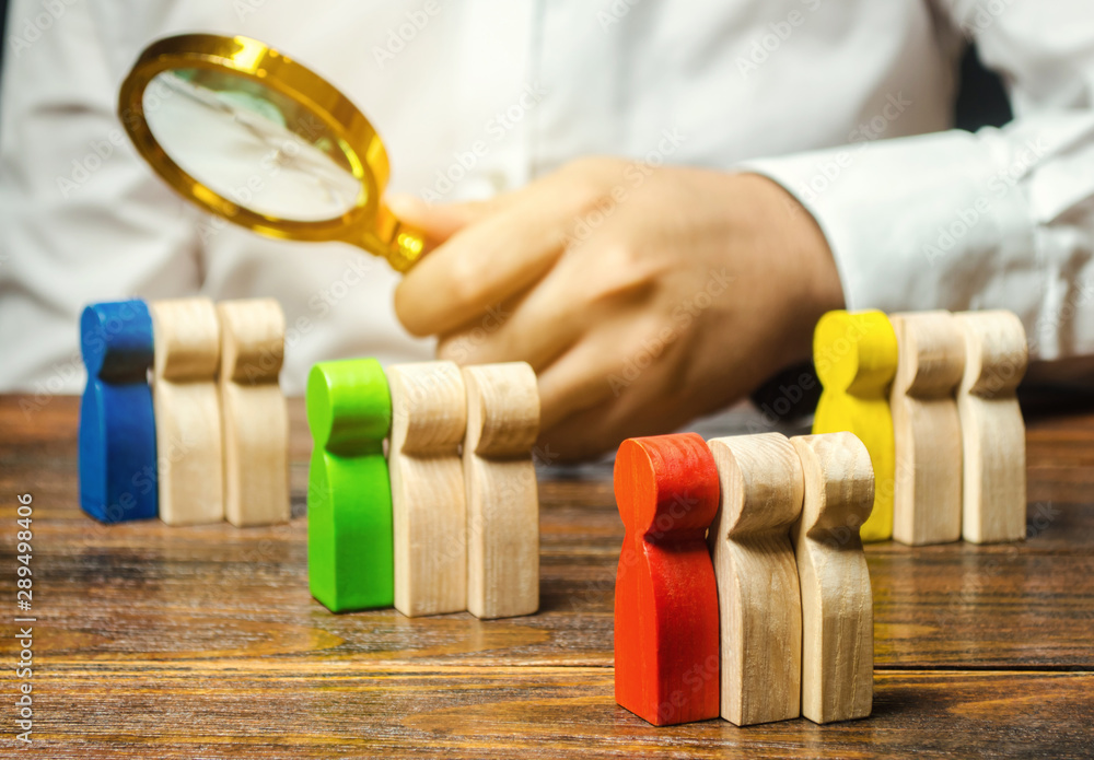 Groups of multicolored wooden people and businessman. The concept of market segmentation. Target audience, customer care. Market group of buyers. Customer relationship management. Selective focus
