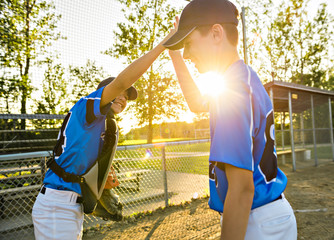 Two childrens baseball players standing together on the playground