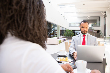 Wall Mural - Business partners meeting at breakfast. Business man sitting at table with laptop, his female colleague drinking coffee. Corporate breakfast concept