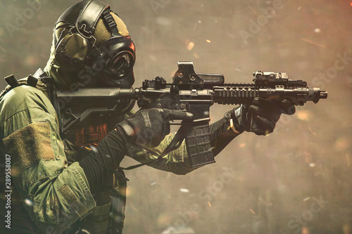 Fotomural Elite special unit soldier with gasmask is holding assault rifle and aiming at t