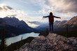 © edb3_16 - Adventurous girl with open arms standing on the edge of a cliff overlooking the beautiful Canadian Rockies and Peyto Lake during a vibrant summer sunset. Taken in Banff National Park, Alberta, Canada.