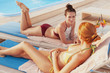 © Ihor - Two female friends sunbathing at the poolside. Beautiful women in bikinis relaxing near the swimming pool together, copy space. Friendship, recreation concept