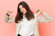 © Asier - Young brunette business woman against a pink background showing thumb down and expressing dislike.