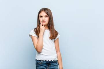 Wall Mural - Cute girl looking sideways with doubtful and skeptical expression.