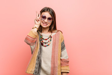 Wall Mural - Little hippie girl showing victory sign and smiling broadly.