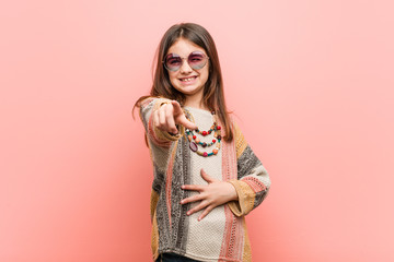 Wall Mural - Little hippie girl points with thumb finger away, laughing and carefree.