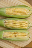 Fototapeta Desenie - Closeup of raw corn cobs with straw over wood