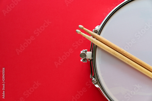 Fotomural Drum and drum stick on red table background, top view, music concept