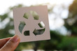 © panadda - Hand holding recycling symbol created with paper cut and landscape on background, Concept of environmental conservation and protection.