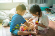 © themorningglory - Asian cute little children playing with toy box while sitting on wood floor