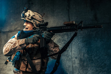 Wall Mural - Young man in military outfit a mercenary soldier in modern times on a dark background in studio