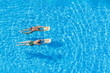© R - Two women swimming in the pool on a sunny day.