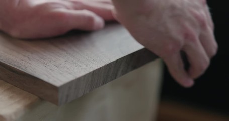 Poster - Slow motion woodworker hand sanding walnut board with sand block