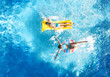 © Iuliia Sokolovska - Children in swimming pool aerial drone view fom above, happy kids swim on inflatable ring donut and mattress, active girls have fun in water on family vacation on holiday resort