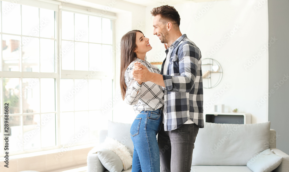 Happy young couple dancing at home