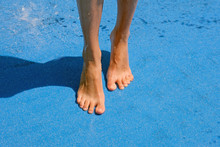 Female Wet Feet On A Blue Background. Tanned Legs, The Girl Is Standing On Socks Near The Fountain.