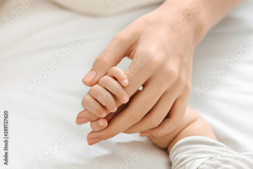 Fotomural Tiny fingers of newborn baby holding mother's hand, closeup