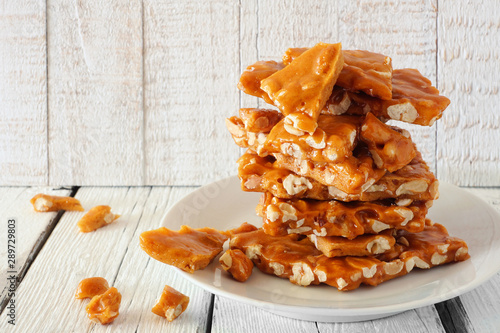 Stack of traditional peanut brittle candy pieces against a white wood background