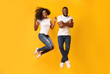 © Prostock-studio - Funny african couple jumping in the air over yellow background
