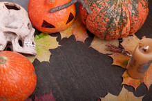 Ceramic Skull, Candle, Halloween Pumpkins On A Dark Brown Table Background, Autumn Leaves And Cones, Copy Space, Top View.