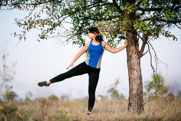 Wall Mural - Fit woman runner doing warming-up exercises, preparing for morning workout in the park. Street fitness, sport, exercising, people and healthy lifestyle concept