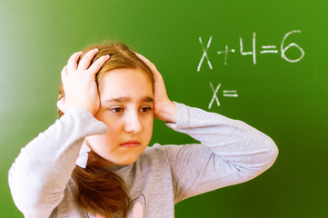 Schoolgirl solves a math problem on the blackboard during the lesson.